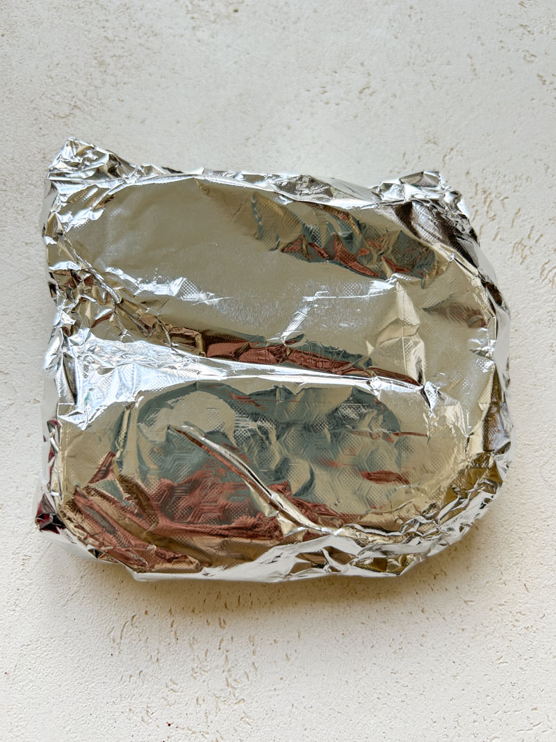 Aluminium foil sealed, with cooked chicken breasts in it.
