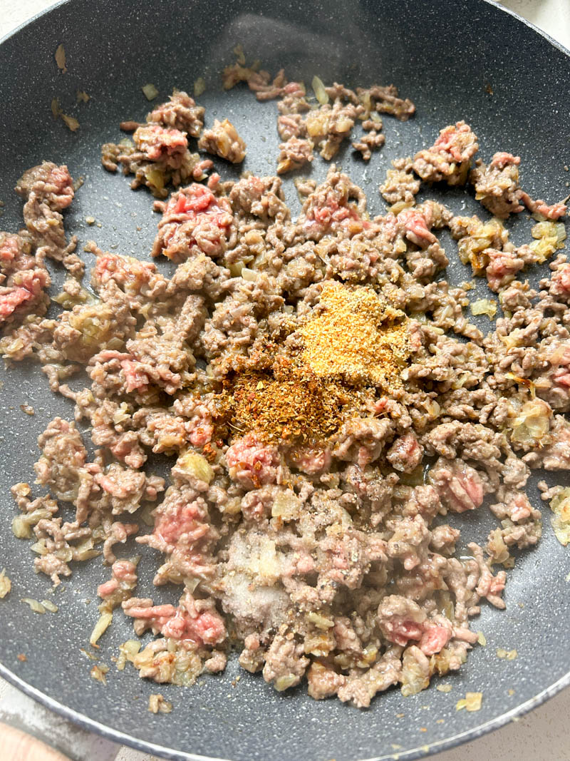 Garlic powder and Italian seasoning added to the frying pan of cooked ground beef.