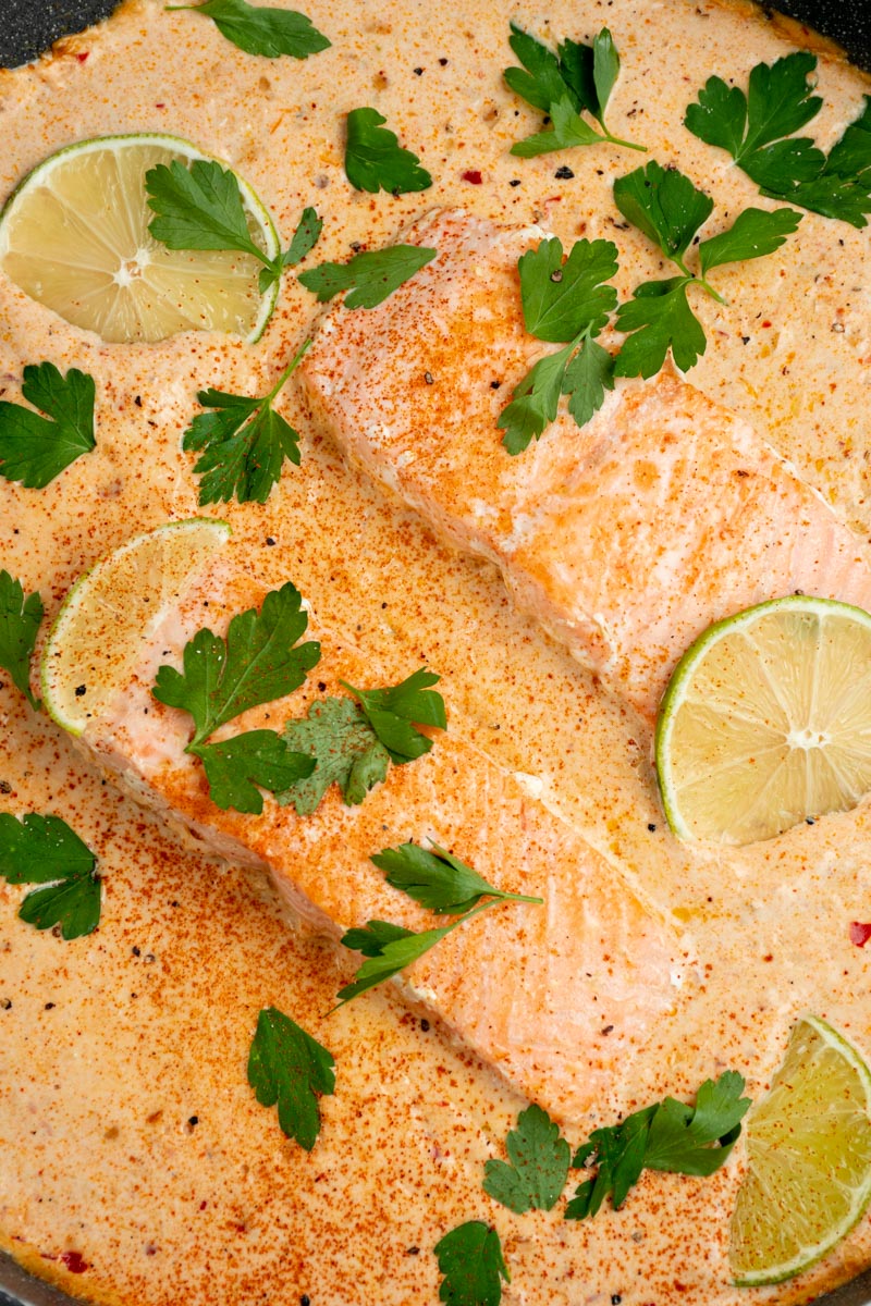 Salmon fillets in a large pan of creamy coconut curry sauce.