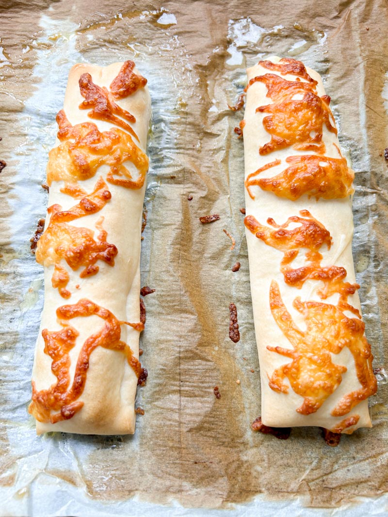 Cheese stuffed breadsticks after cooking, on parchment paper.