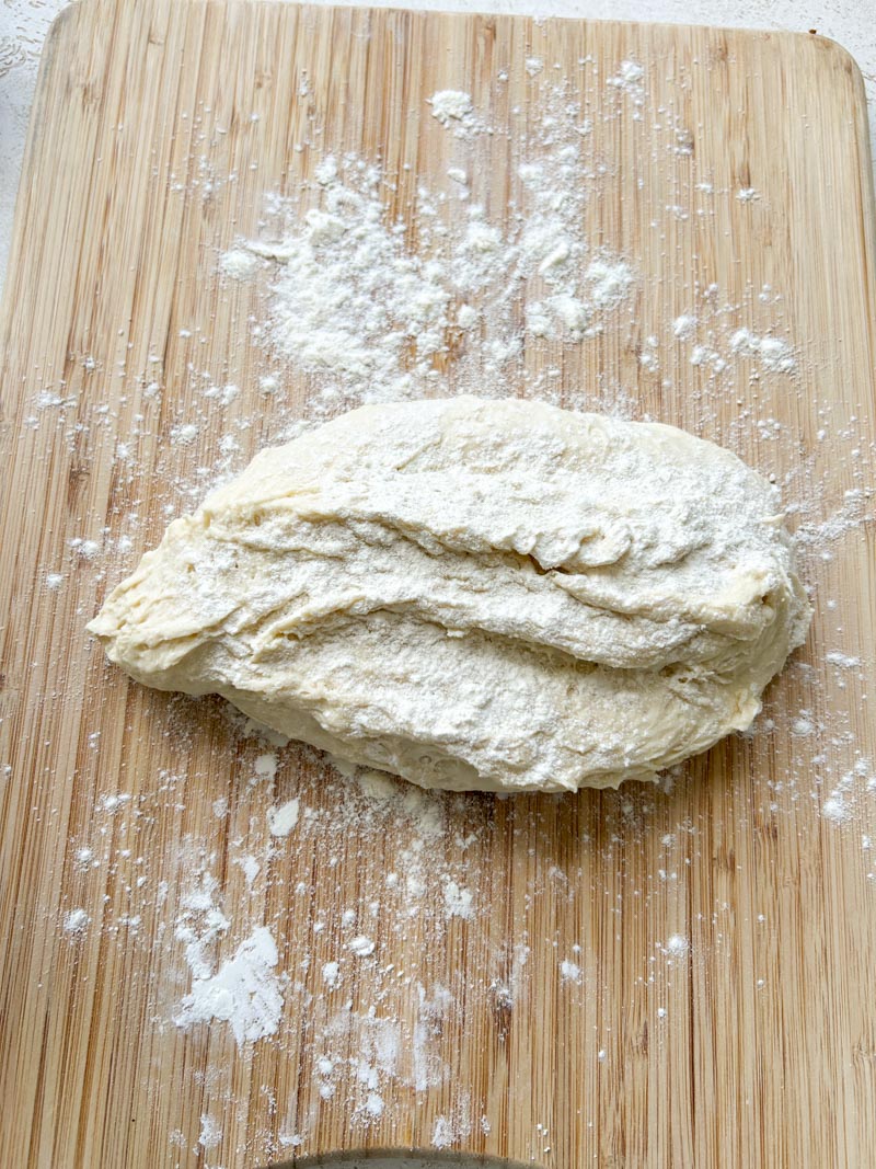 La pâte du Khachapuri, avec un peu de farine, sur une surface en bois légèrement farinée.