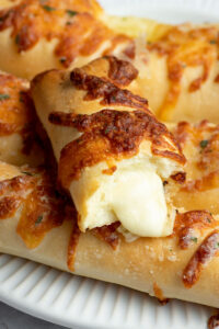 Cheese stuffed breadstick with melted mozzarella coming out of it.