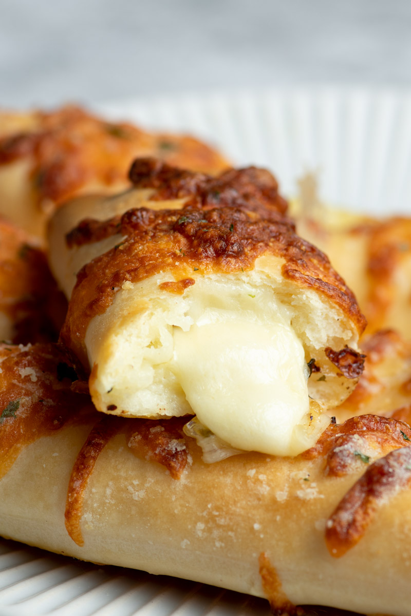 Cheese stuffed breadstick with melted mozzarella coming out of it.
