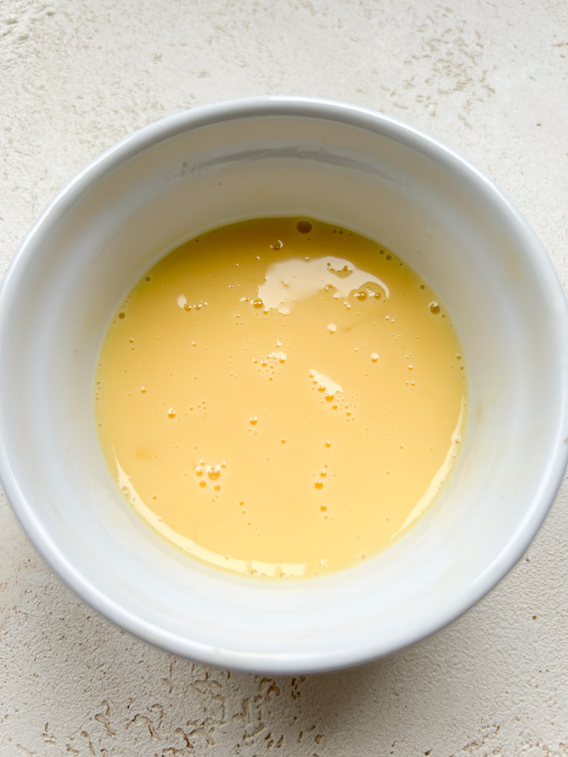 Mélange d'œuf et de lait, dans un petit bol blanc.