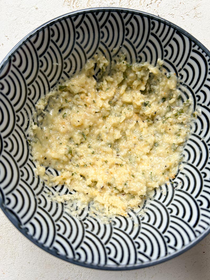 Le beurre fondu, le Parmesan, l'ail en poudre, le persil frais, le sel et le poivre noir sont dans un petit bol.
