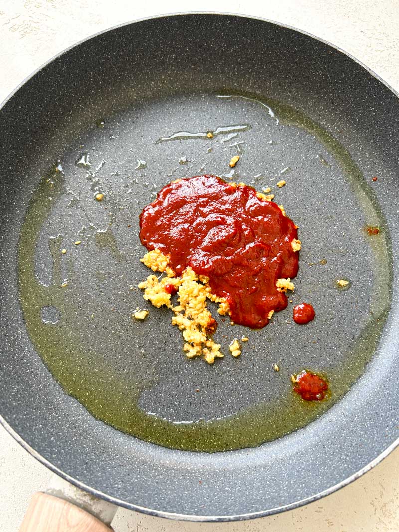 Gochujang added to the skillet of cooked garlic.
