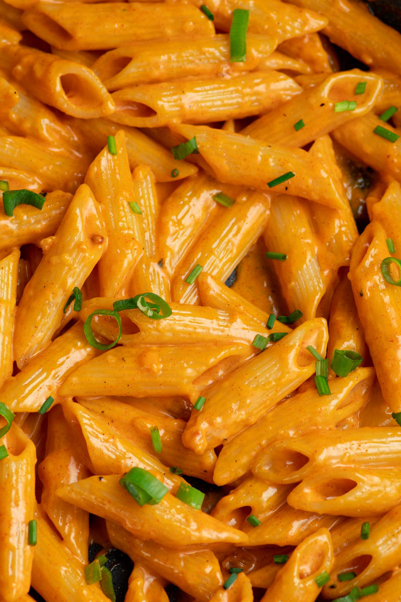 Creamy Gochujang pasta in a large skillet with spring onions and fresh chopped chives.