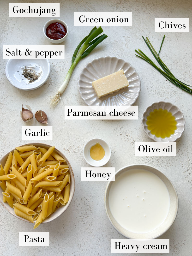 Ingredients to make Gochujang pasta in white and beige bowls and plates.