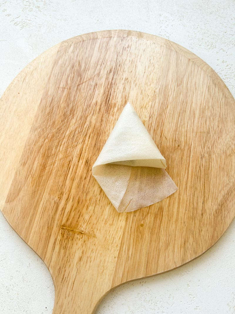 Triangle de feuille de brick, sur la planche en bois ronde.
