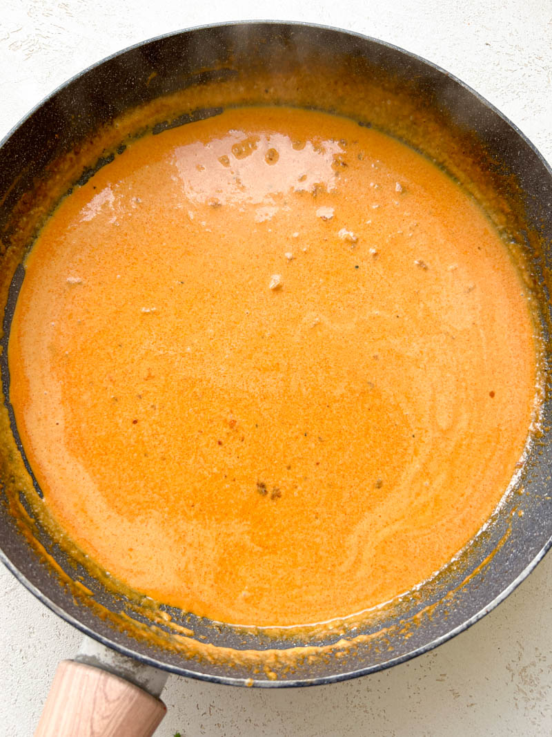 La crème liquide, le miel, le sel, le poivre noir et l'eau de cuisson des pâtes sont mélangées dans la poêle pour créer la sauce crémeuse.