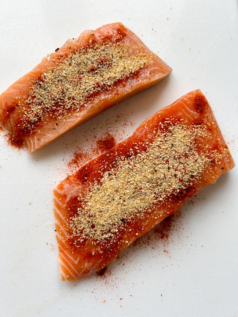 Deux filets de saumon assaisonnés avec de l'ail en poudre, du paprika, du sel et du poivre.