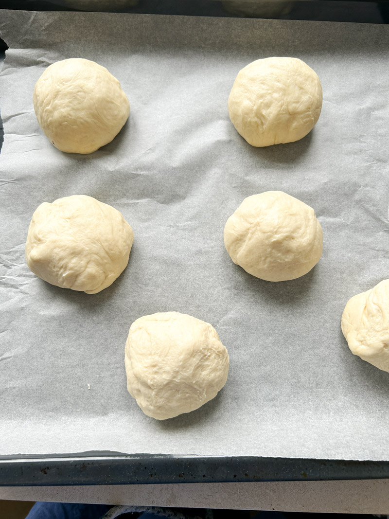 Six balls on a baking tray lined with parchment paper.