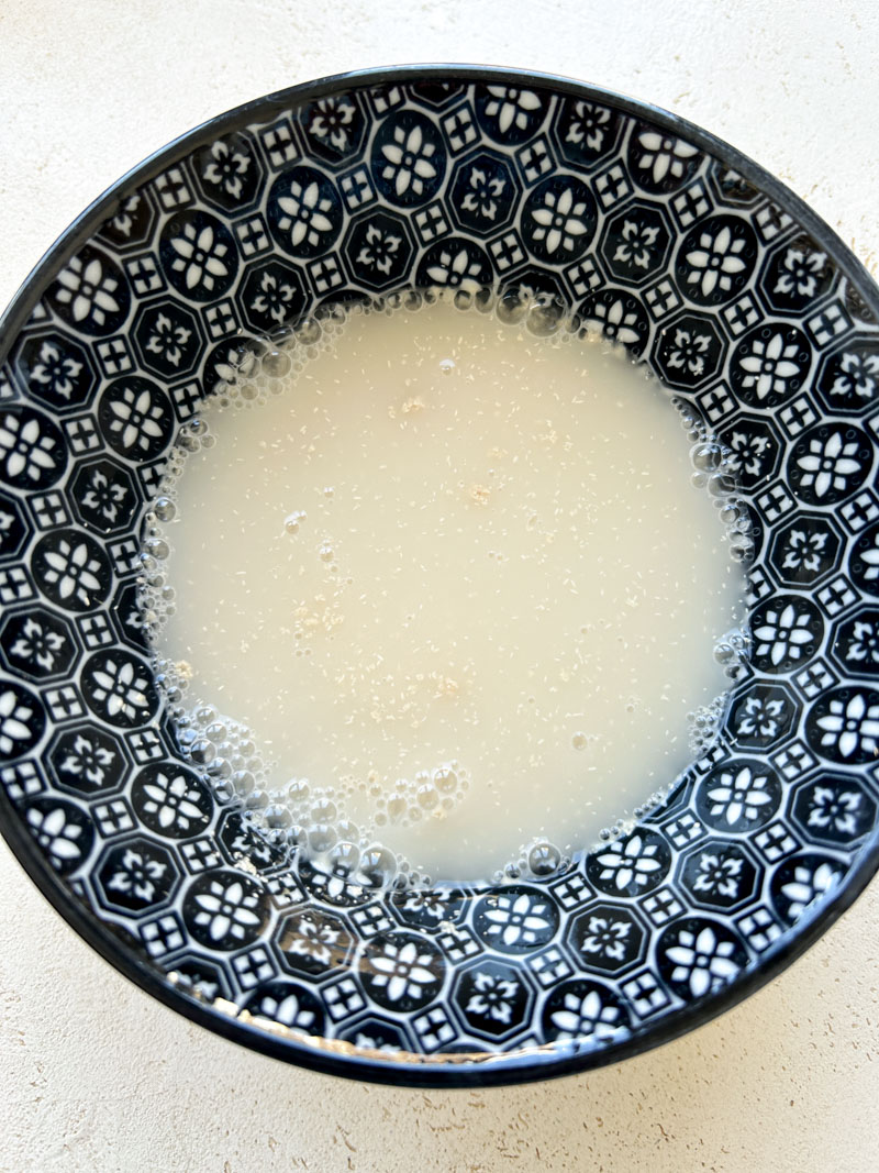 L'eau, le sucre et la levure boulangère sont mélangés dans un bol bleu.