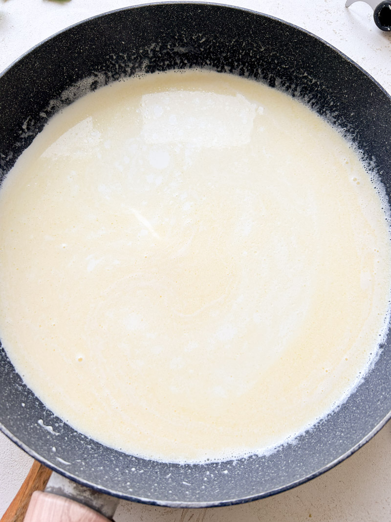 Homemade Alfredo sauce ready in a large grey pan.