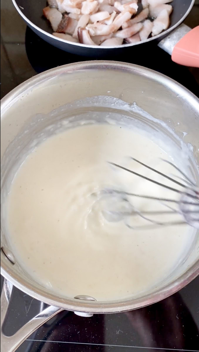 Béchamel sauce ready in the pan, mixed with a whisk.