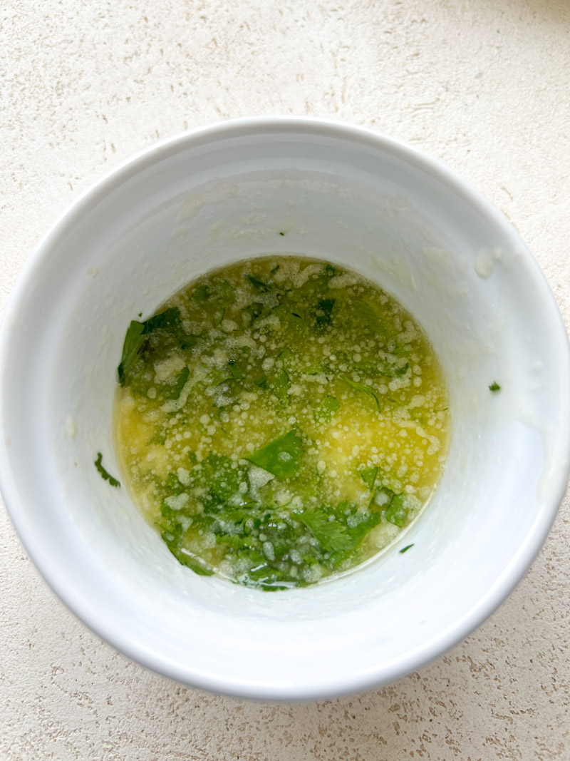 Melted butter, minced cilantro and pressed garlic in a small white ramekin.