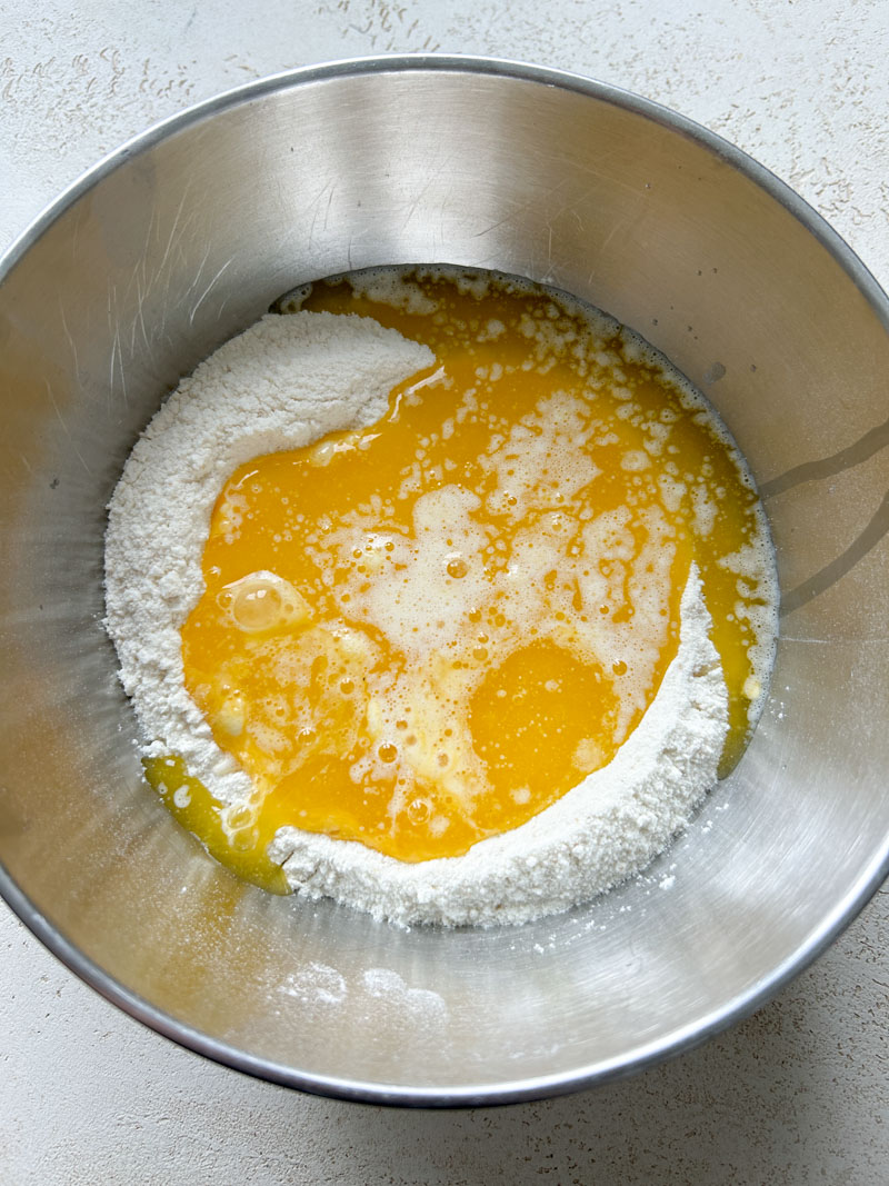 The melted butter was added to the well of flour and beaten eggs.