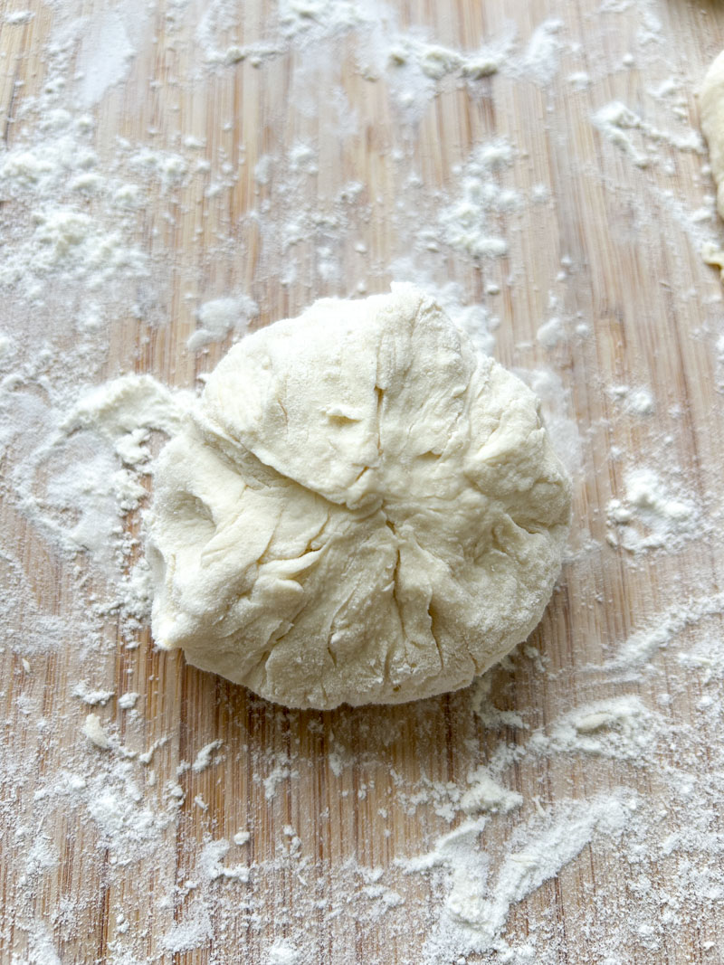 Ball of dough on floured wooden board.