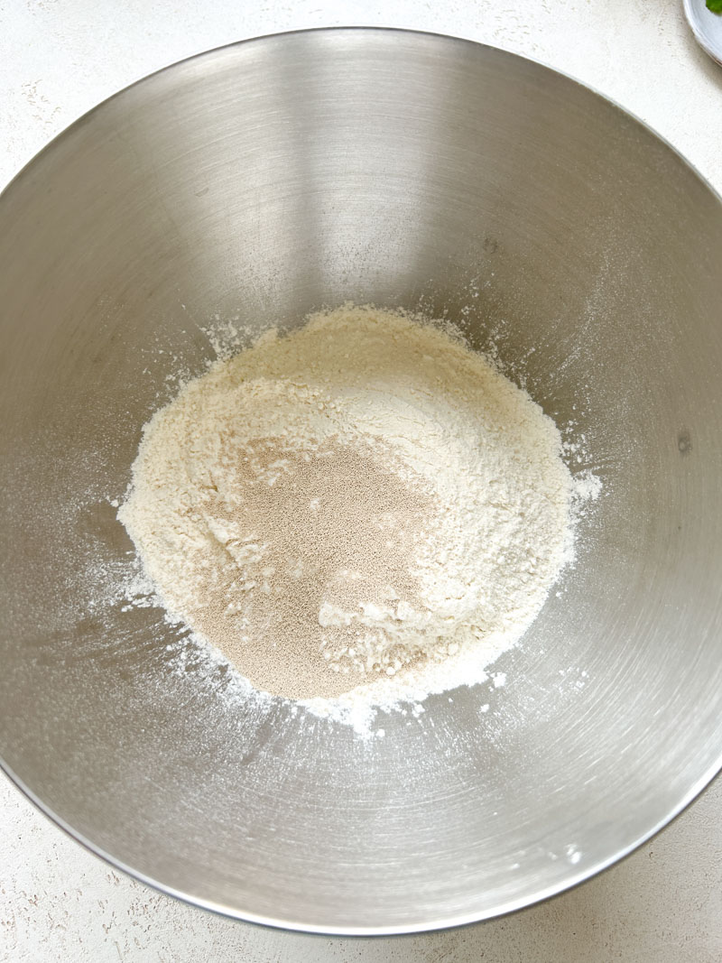 Flour and instant dry yeast in a large stainless steel bowl.