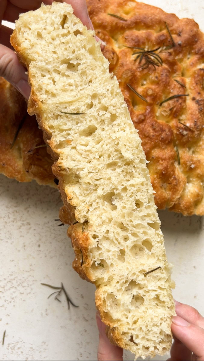 A slice of focaccia with an appetizing honeycombed crumb.