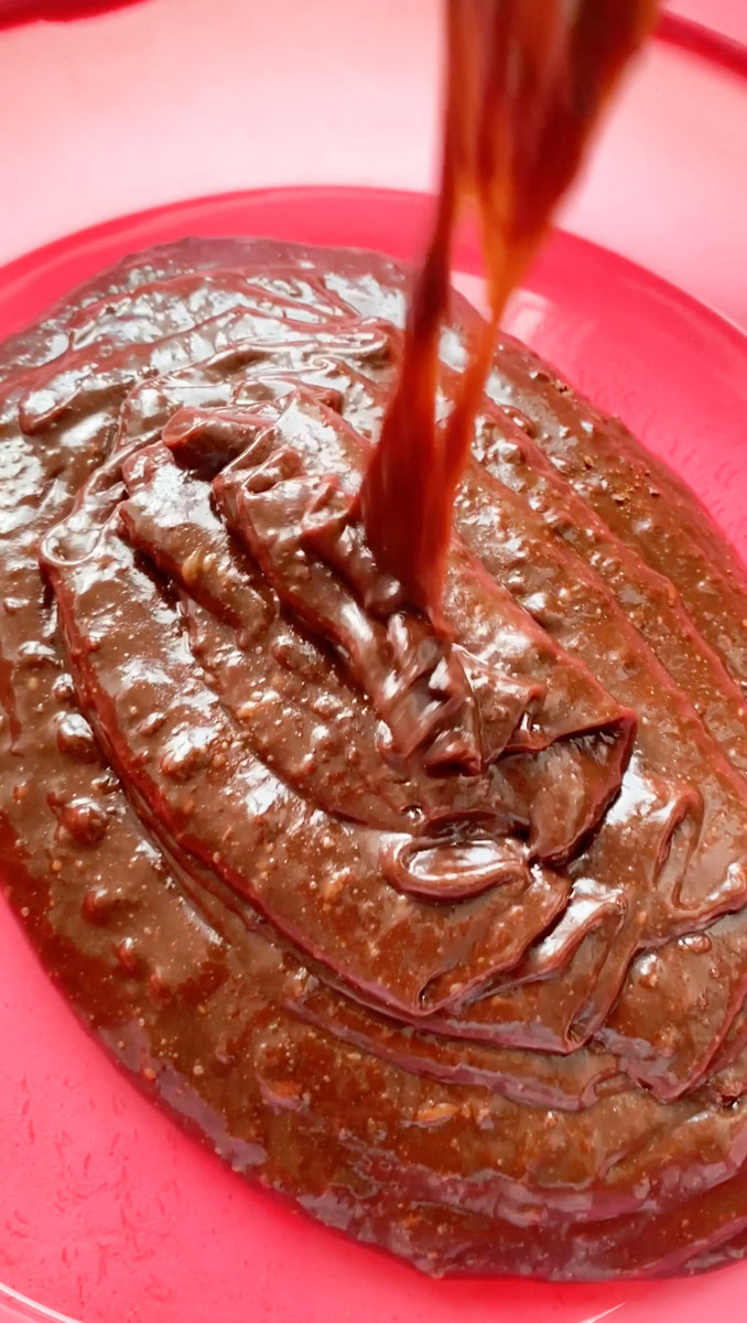 Pâte du fondant au chocolat versée dans un moule rose.