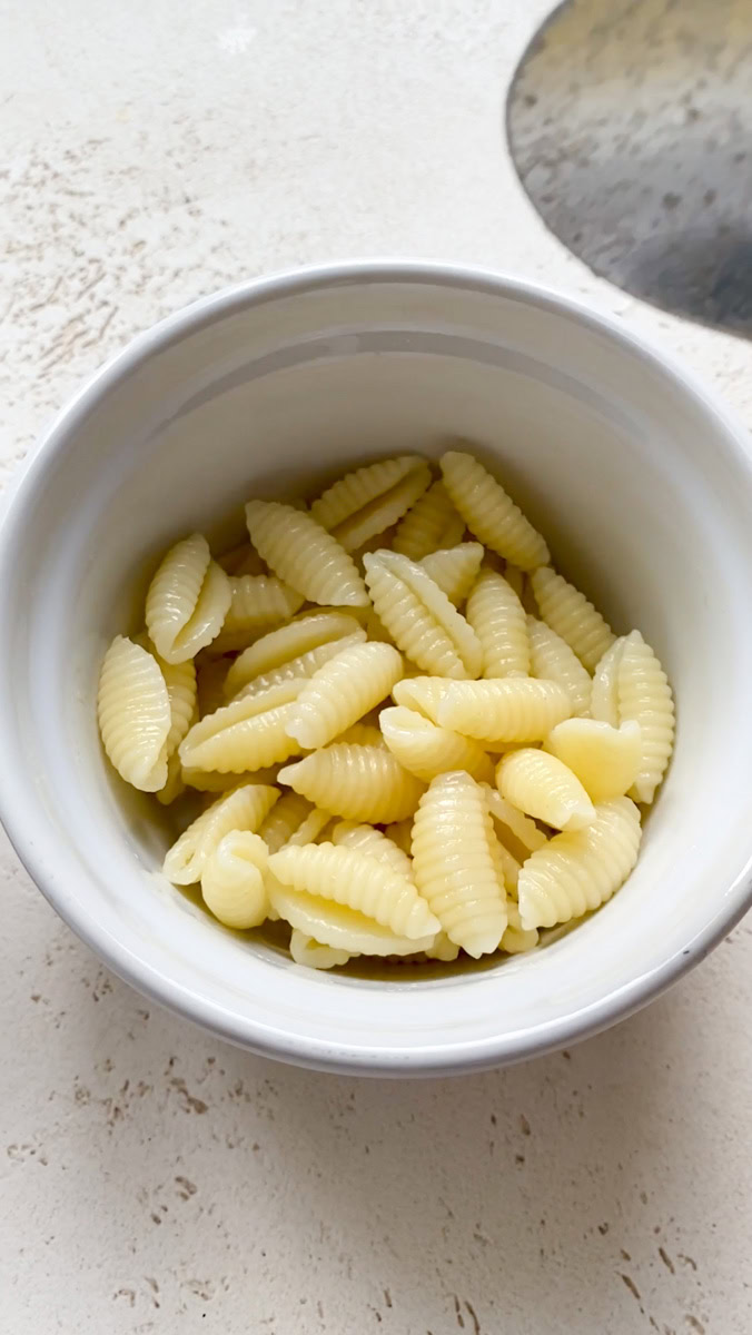 Some cooked and drained pasta in a white ramekin.