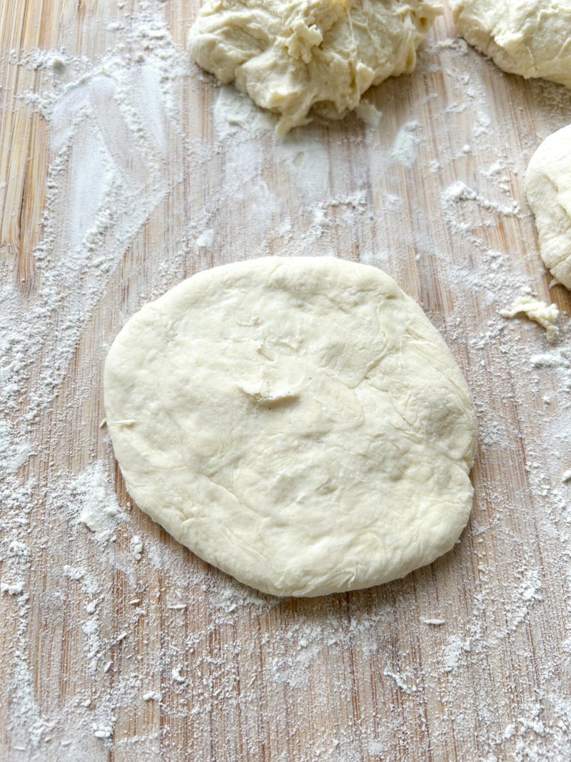Dough piece lowered on the floured wooden board.