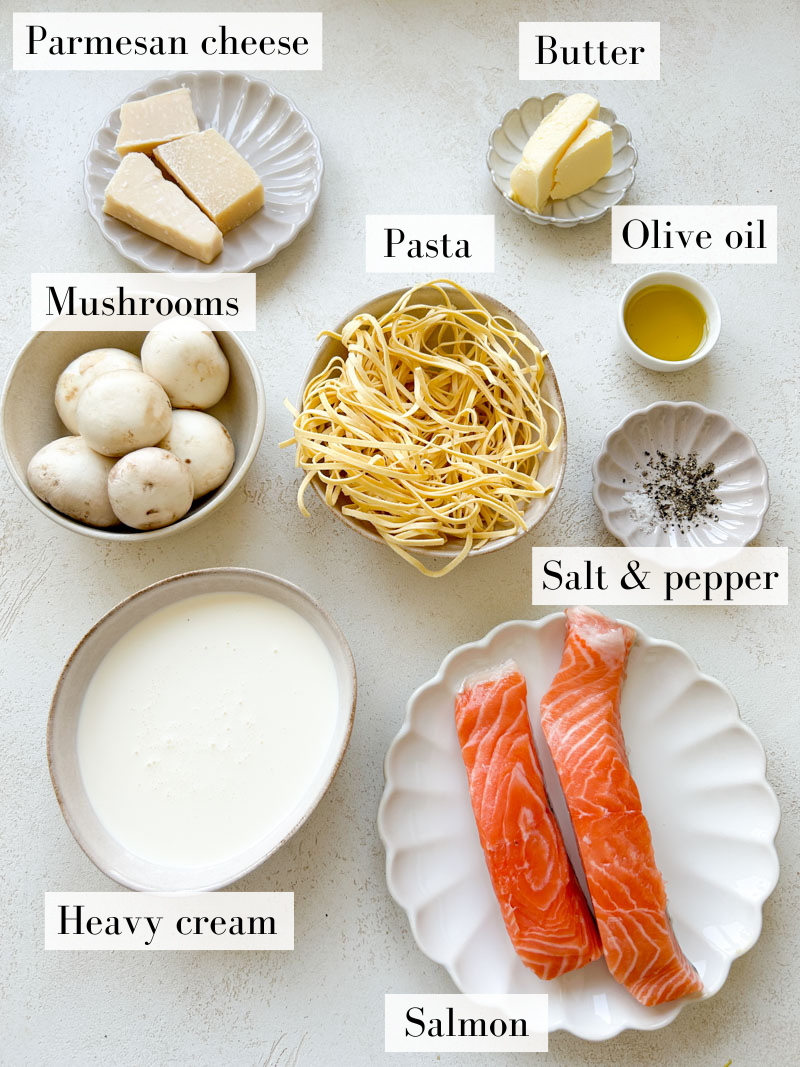 Salmon Alfredo pasta's ingredients in beige and white bowls and plates.