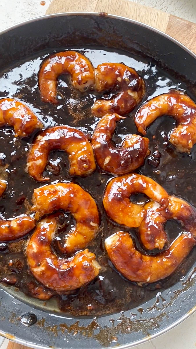 The shrimp are cooked and coated with Teriyaki sauce in the pan.