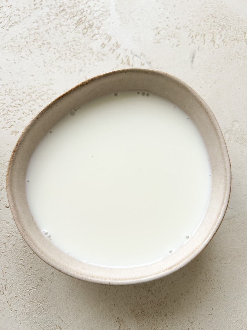 Warm water and Greek yogurt mixed in a beige bowl.