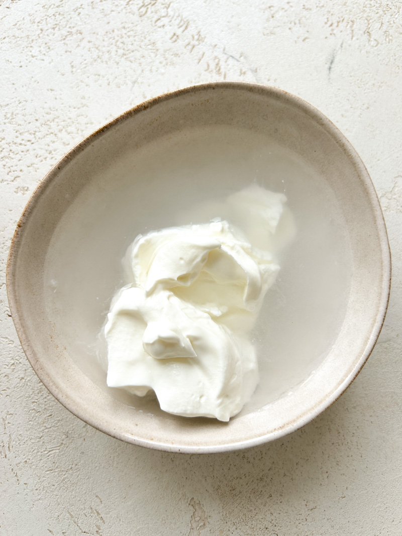 Eau tiède et yaourt grec dans un bol beige.