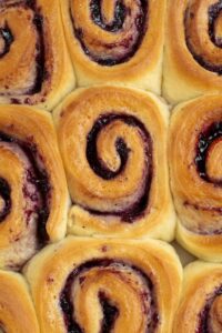 Nine blueberry rolls placed together in a large ovenproof dish.