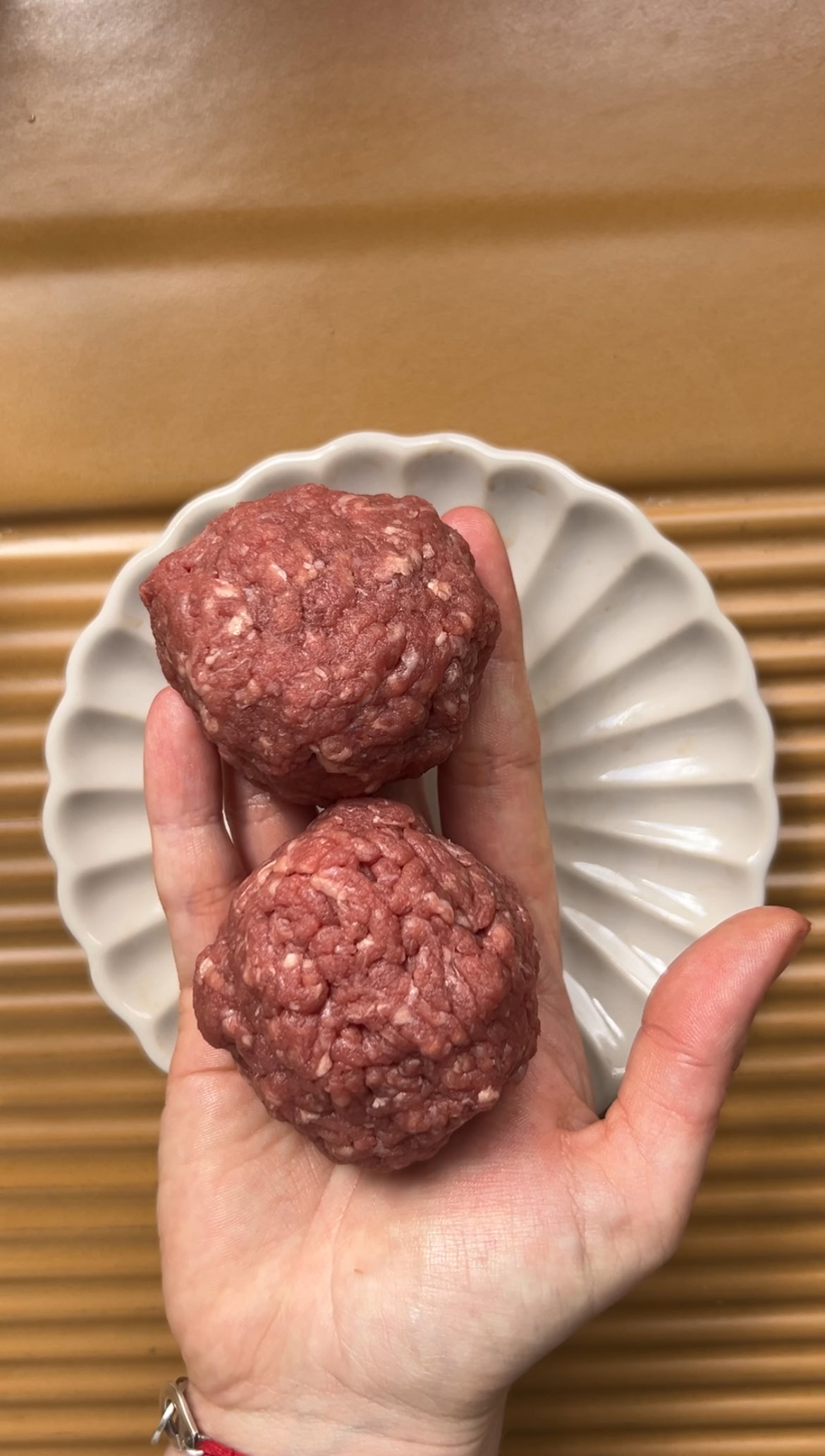 Two balls of uncooked minced meat held in one hand.