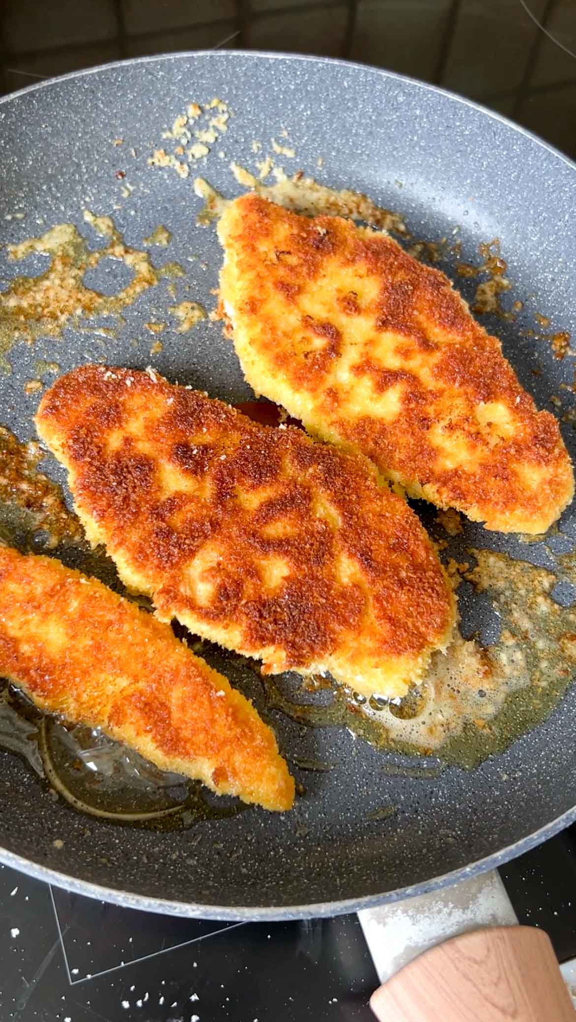 Chicken cutlets in a frying pan with olive oil.
