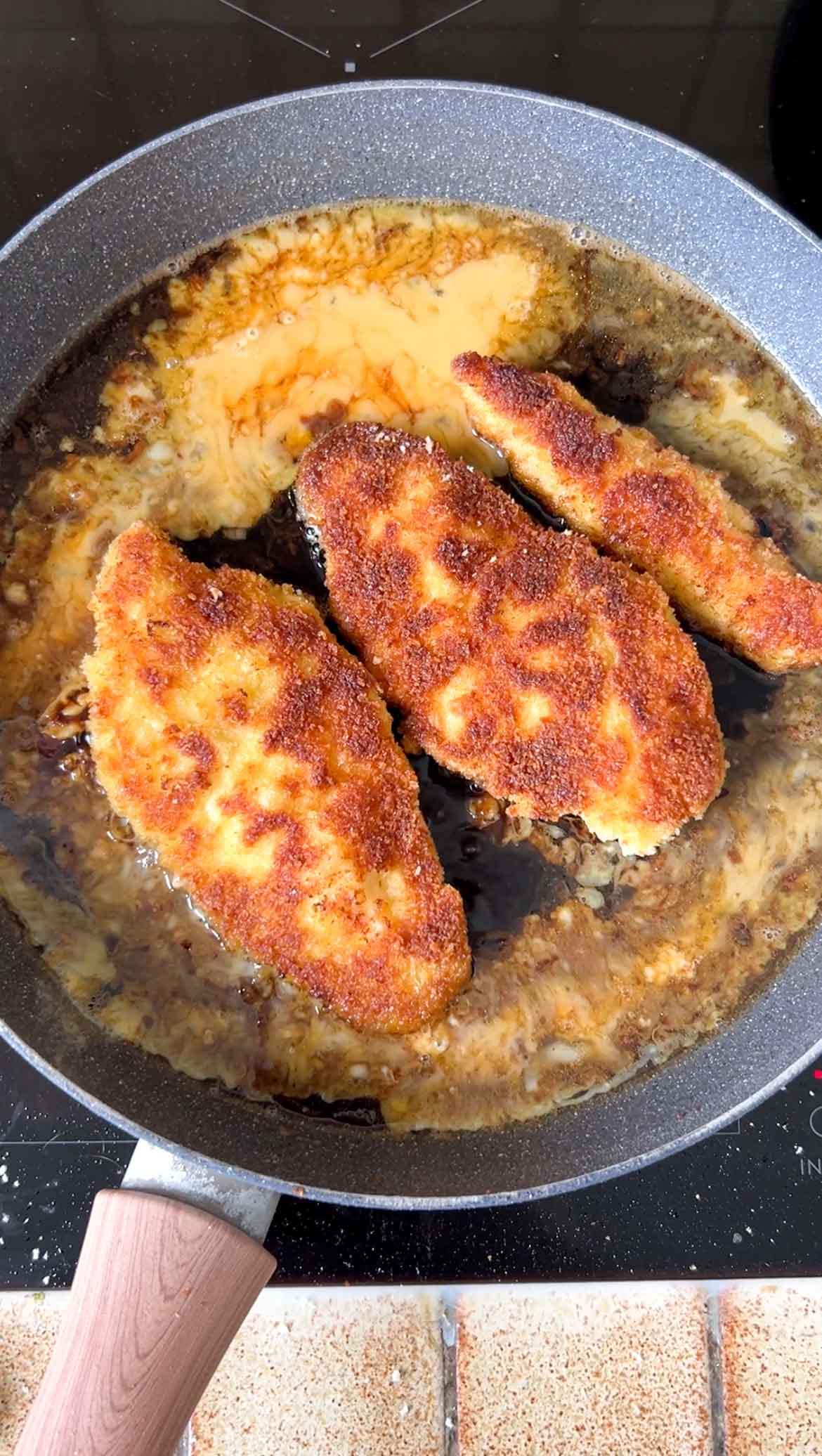 Egg mixture added to the pan of sauce and breaded chicken cutlets.