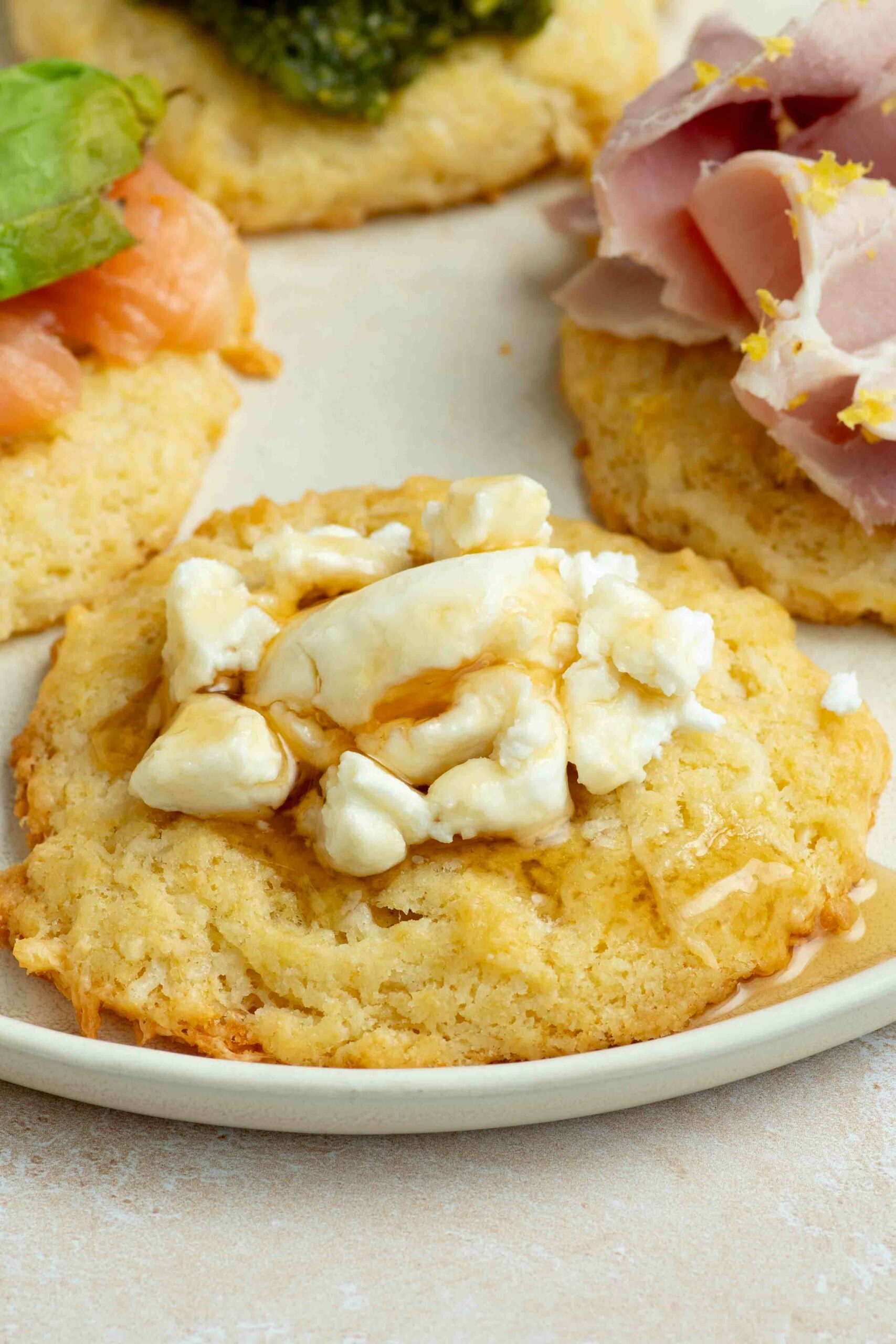 A cookie placed on a plate and garnished with chunks of goat cheese and a drizzle of honey.