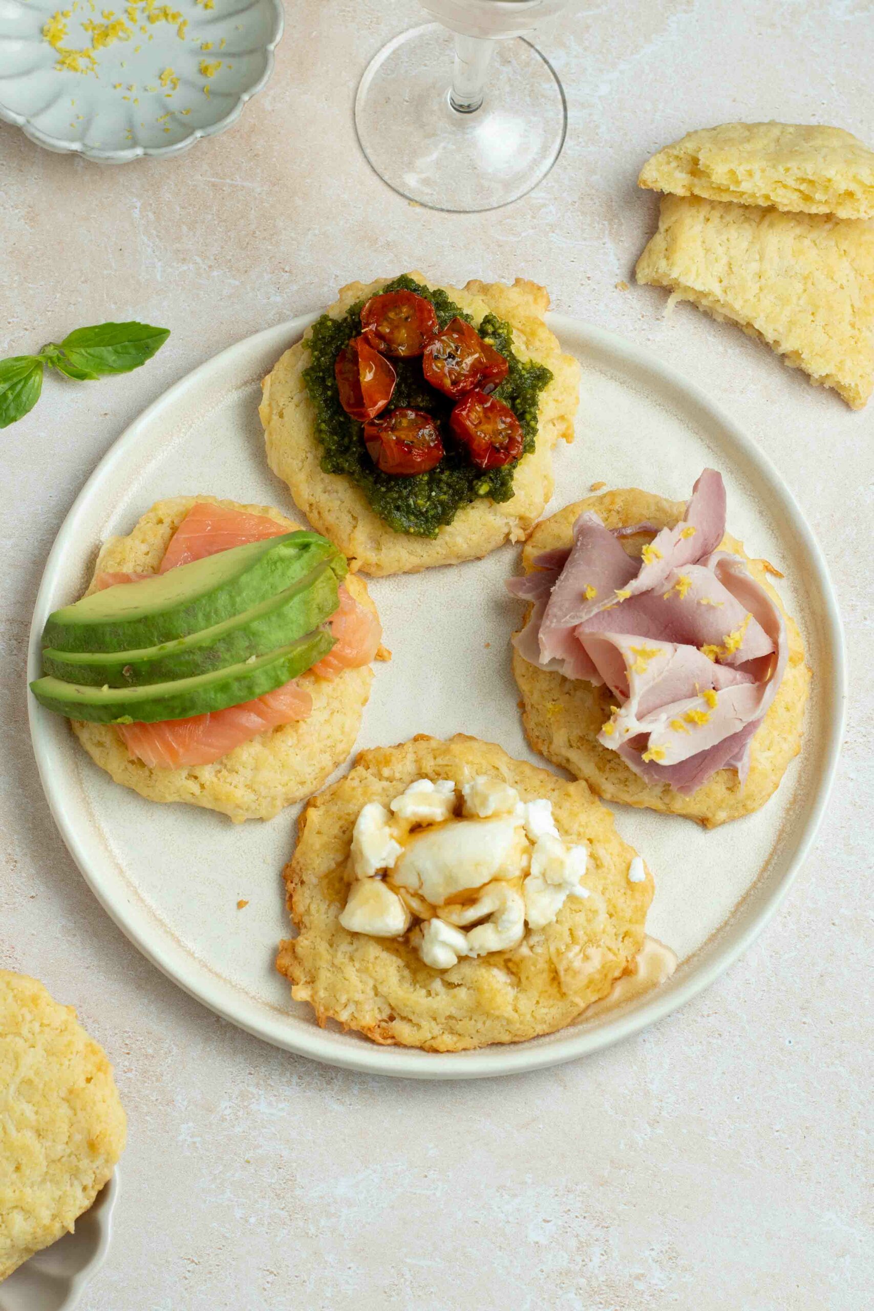 Four savory cookies in a beige plate with four different toppings.