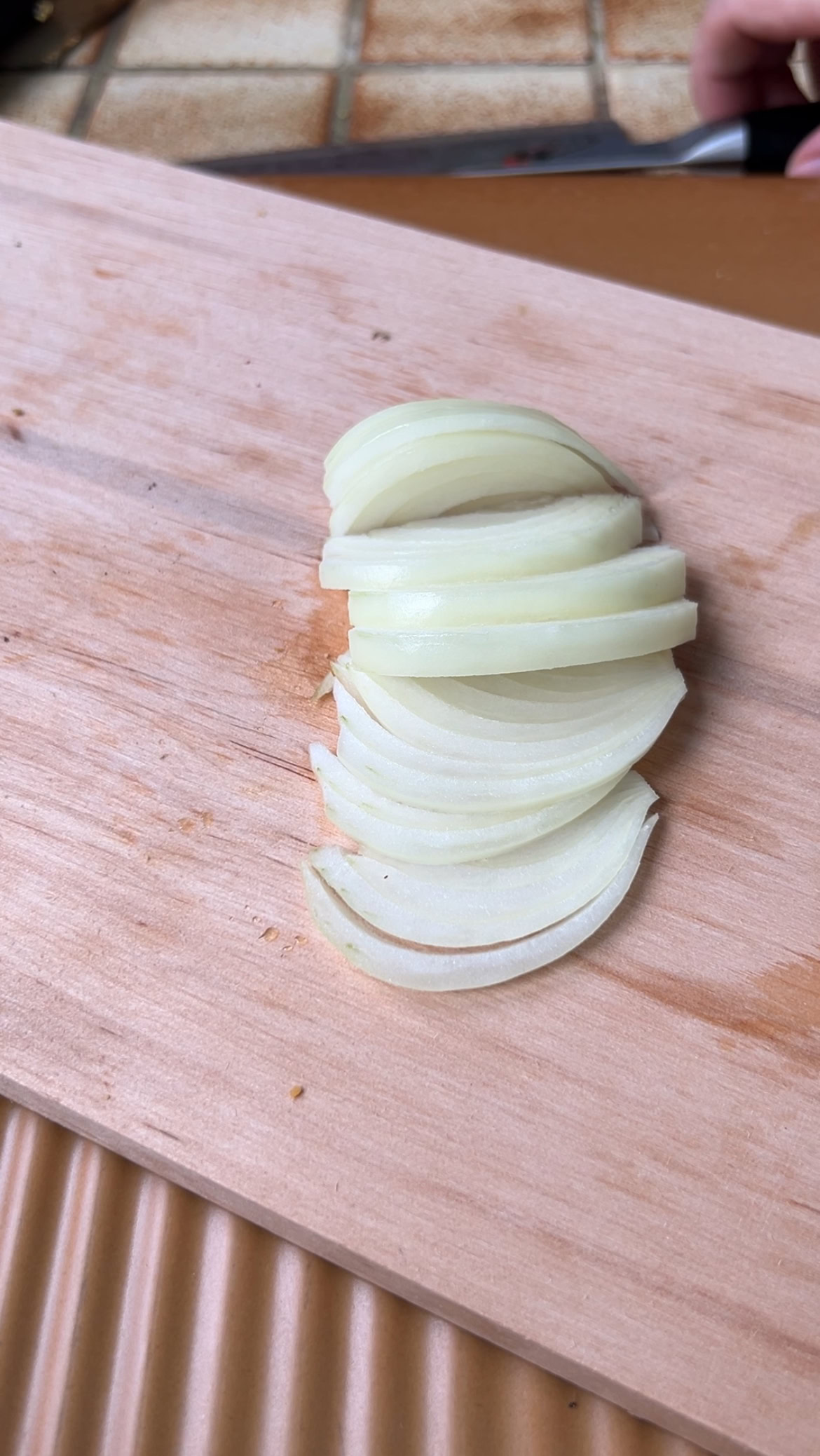 Oignon coupé en lamelles sur une planche en bois.