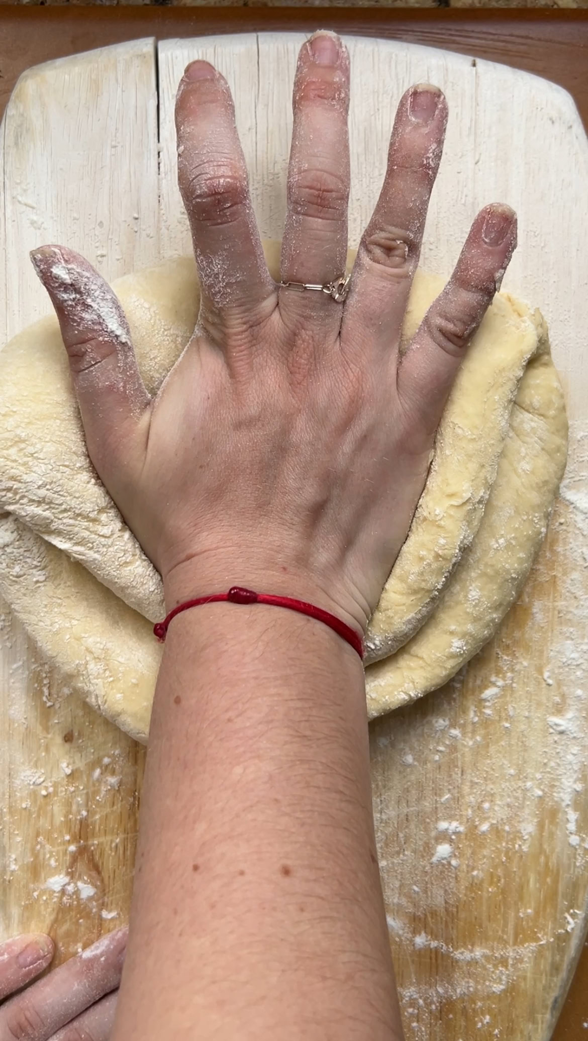 Une main pétrit la pâte de bas en haut.