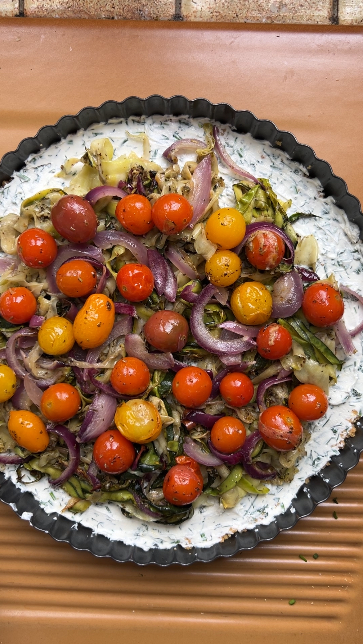 The roasted vegetables are added to the cream cheese mixture in the tart tin.