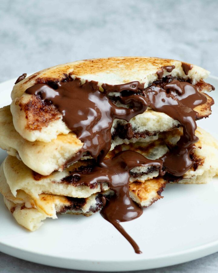 Quatre demi-pancakes empilés les uns sur les autres et dégoulinant de Nutella coulant.