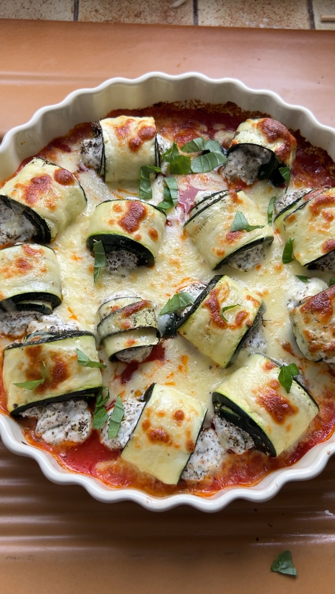 Zucchini involtini in their dish, just out of the oven, with melted mozzarella on top.