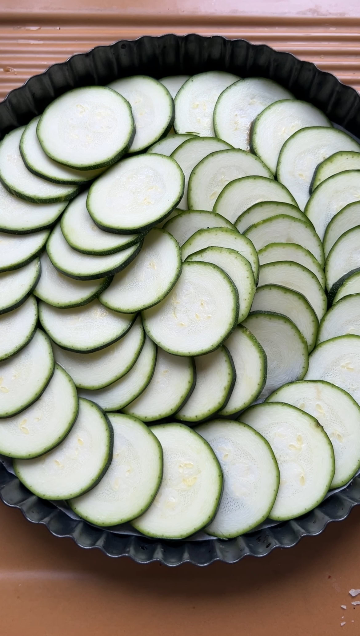 Slices of zucchini nicely arranged in the bottom of the tart tin.