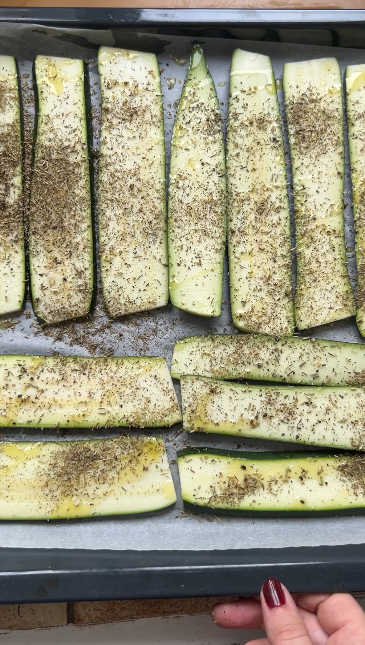 Seasoned zucchini slices, placed on a baking sheet lined with parchment paper.