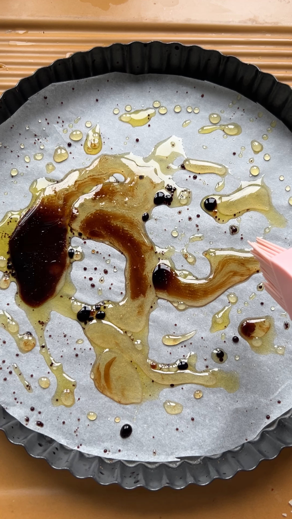 Huile d'olive, miel et vinaigre Balsamique dans le fond d'un moule à tarte recouvert de papier cuisson.