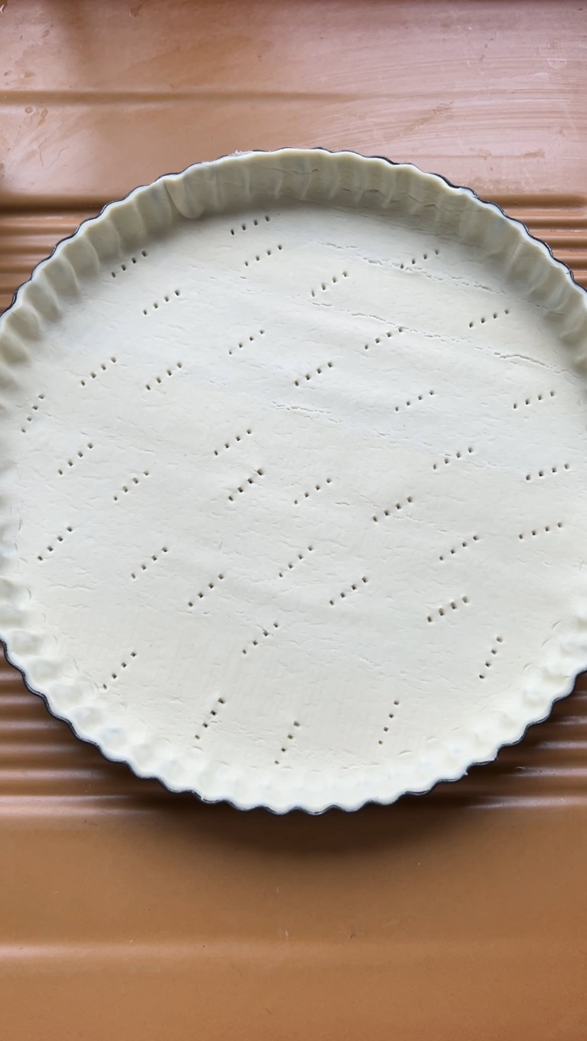 Puff pastry in a black tart tin, with small fork holes.