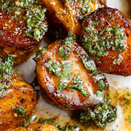 Oven-baked, roasted potatoes on parchment paper covered with a honey, lemon, cilantro and olive oil sauce.