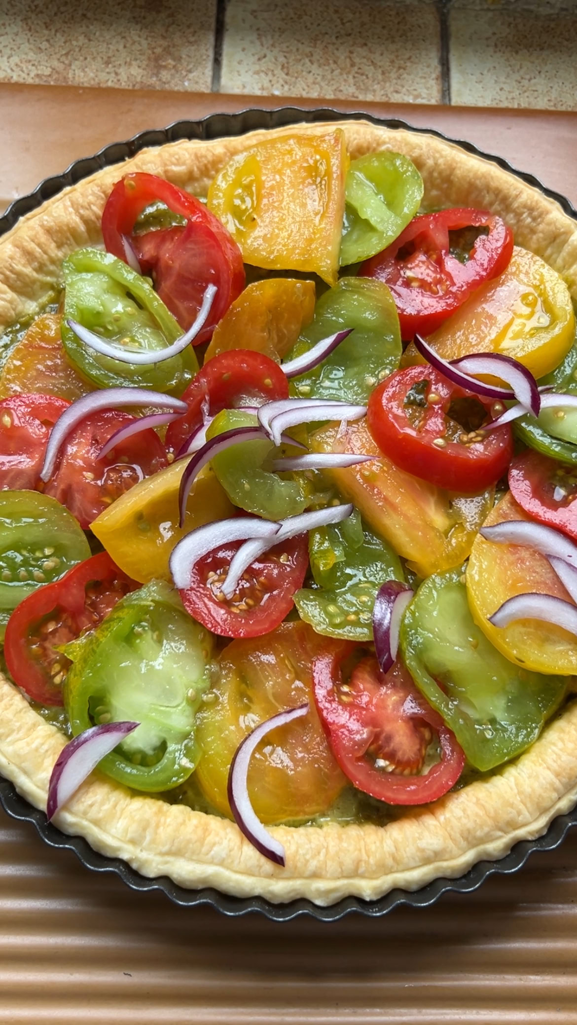 Slices of tomato added to puff pastry, with a few slices of red onion.
