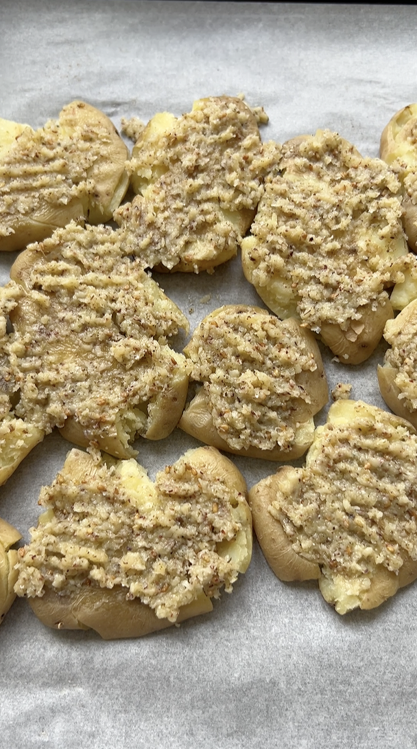 Smashed potatoes on a sheet of parchment paper and covered with a mixture of melted butter, Zaatar and garlic.