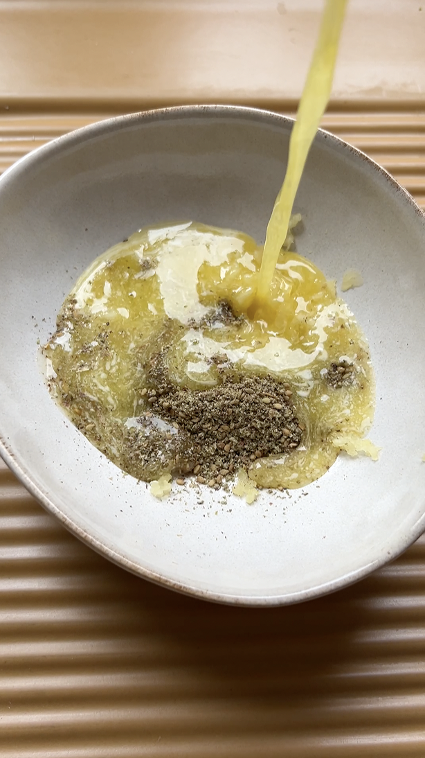 Melted butter poured into a beige bowl of Zaatar.